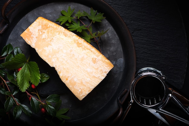 Food Concept organic Parmesan Cheese in rustic iron tray on black slate stone background with copy space