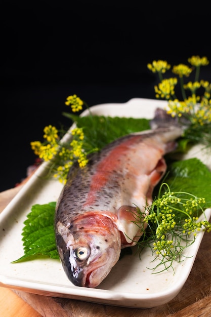 Food concept White Trout fish in in ceramic plate on wooden board on black background with copy space