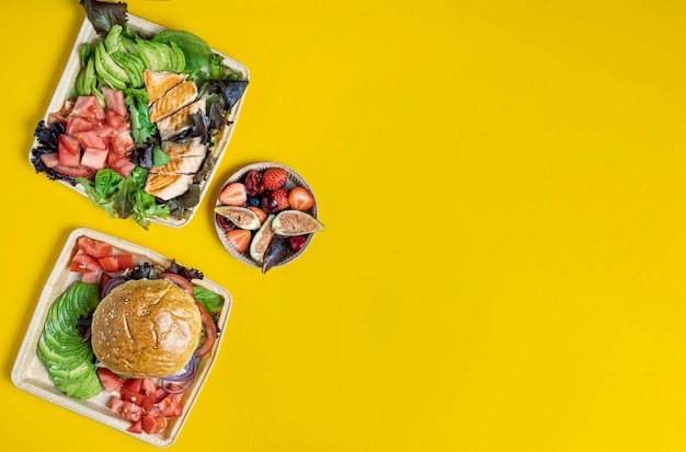 Food containers with healthy takeaway food on yellow background top view mockup