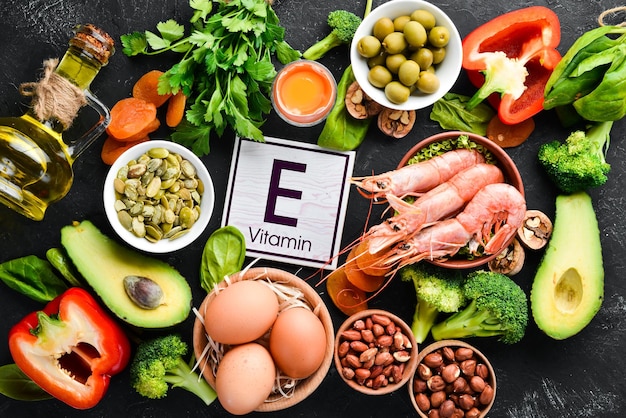 Food containing natural vitamin E Spinach parsley shrimp pumpkin seeds eggs avocados broccoli Top view On a black background