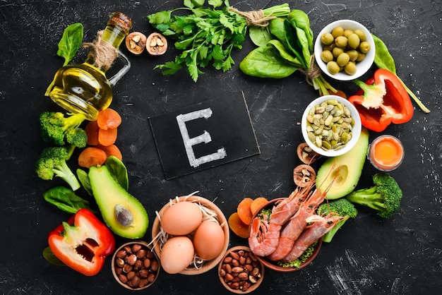 Food containing natural vitamin E Spinach parsley shrimp pumpkin seeds eggs avocados broccoli Top view On a black background