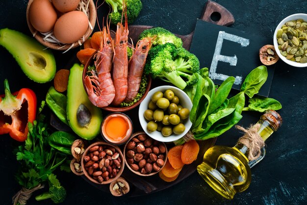 Food containing natural vitamin E Spinach parsley shrimp pumpkin seeds eggs avocados broccoli Top view On a black background