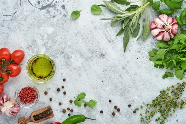 Food cooking background. Fresh saffron, garlic, cilantro, basil, cherry tomatoes, peppers and olive oil, spices herbs and vegetables at light grey slate table. Food ingredients top view.