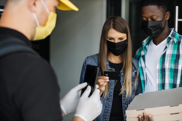 Food delivery to a beautiful Caucasian woman with African husband in face masks