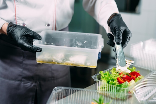 Food delivery in the restaurant. The chef prepares food in the restaurant and packs it in disposable dishes.