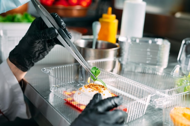 Food delivery in the restaurant. The chef prepares food in the restaurant and packs it in disposable dishes.