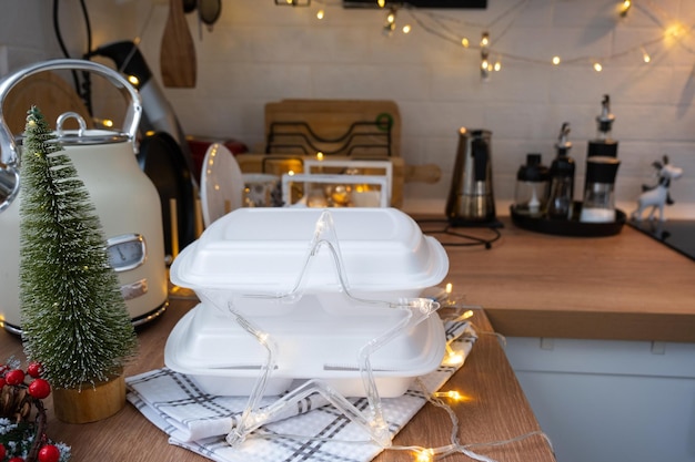 Food delivery service containers on table white scandi festive kitchen in christmas decor Eve New year saving time too lazy to cook hot order disposable plastic box in fairy light mock up