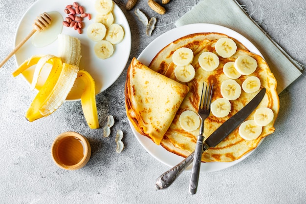 Food, dessert, pastries, pancake, pie. Tasty beautiful pancakes with banana and honey on a concrete background