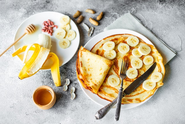 Food, dessert, pastries, pancake, pie. Tasty beautiful pancakes with banana and honey on a concrete background