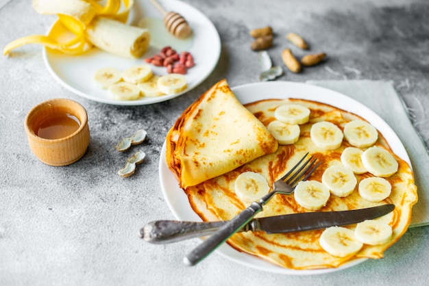 Food, dessert, pastries, pancake, pie. Tasty beautiful pancakes with banana and honey on a concrete background