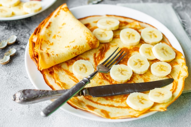 Food, dessert, pastries, pancake, pie. Tasty beautiful pancakes with banana and honey on a concrete background