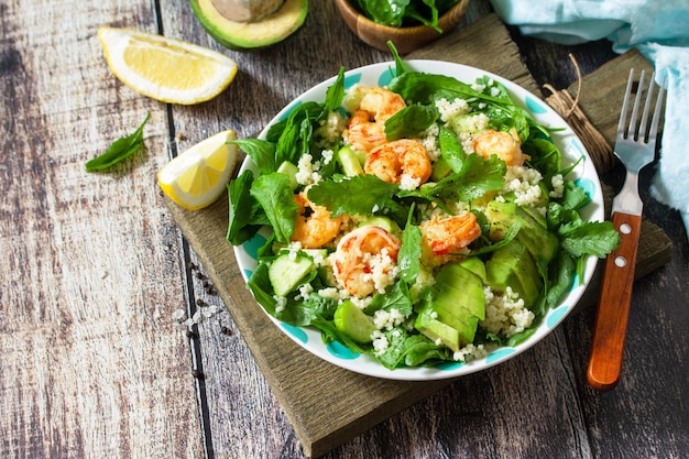 Food dieting concept Couscous salad with arugula avocado and grilled shrimps Copy space