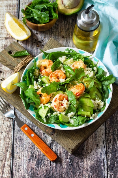 Food dieting concept Couscous salad with arugula avocado and grilled shrimps Copy space