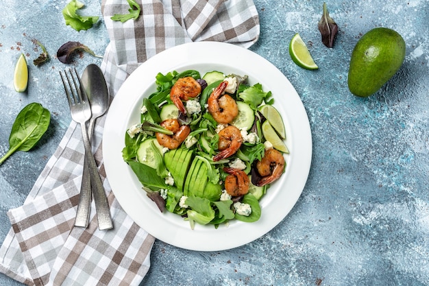 Food dieting concept. Green salad with avocado, blue cheese and smoked shrimps. Delicious breakfast or snack on a light background, top view.