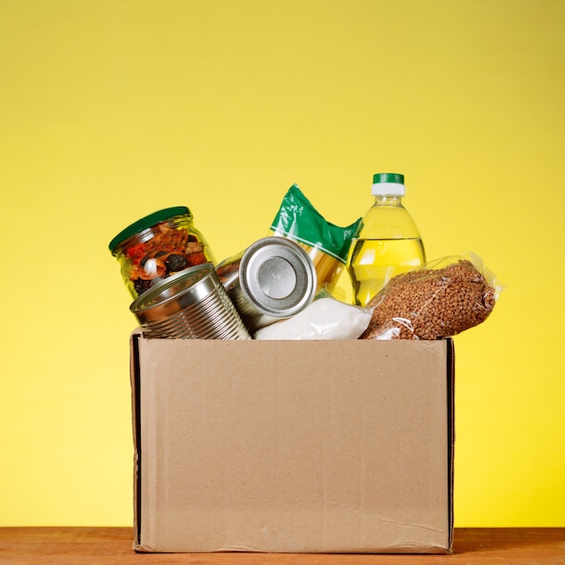 Food Donation concept. Donation Box With food For Donation On Yellow Backround. Assistance To The Elderly In The Context of The Coronavirus Pandemic. square image