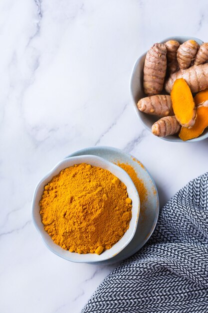 Photo food and drink, diet nutrition, health care concept. raw organic orange turmeric root and powder, curcuma longa on a cooking table. indian oriental low cholesterol spices. copy space background