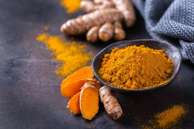 Food and drink, diet nutrition, health care concept. Raw organic orange turmeric root and powder, curcuma longa on a cooking table. Indian oriental low cholesterol spices. Copy space background