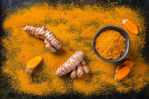 Photo food and drink, diet nutrition, health care concept. raw organic orange turmeric root and powder, curcuma longa on a cooking table. indian oriental low cholesterol spices