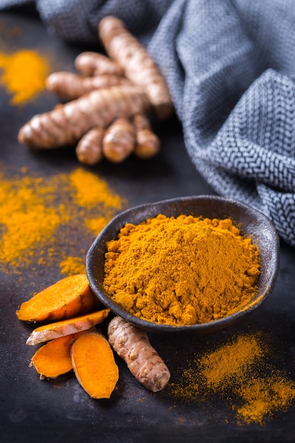 Food and drink, diet nutrition, health care concept. Raw organic orange turmeric root and powder, curcuma longa on a cooking table. Indian oriental low cholesterol spices