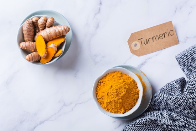 Photo food and drink, diet nutrition, health care concept. raw organic orange turmeric root and powder, curcuma longa on a cooking table. indian oriental low cholesterol spices.