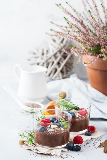 Food and drink healthy eating and dieting concept Homemade chocolate chia pudding with fresh berries and green thyme for breakfast on a cozy kitchen table