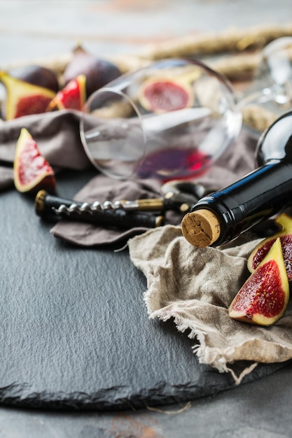 Food and drink still life holidays seasonal harvesting fall autumn concept Bottle corkscrew corks glass of red wine and figs on a grunge table Copy space background