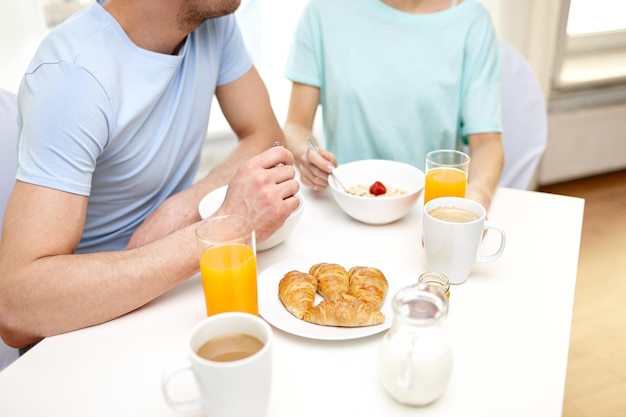 food, eating, people and healthy food concept - close up of couple having breakfast at home