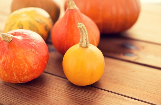 food, harvest, season and autumn concept - close up of pumpkins on wooden table at home