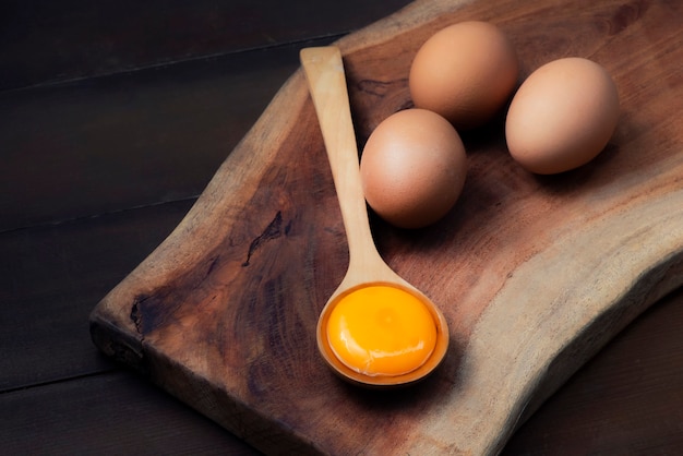 Food ingredients (egg yolks) for serving on a spoon, wooden floor and raw Eggs on wood Background