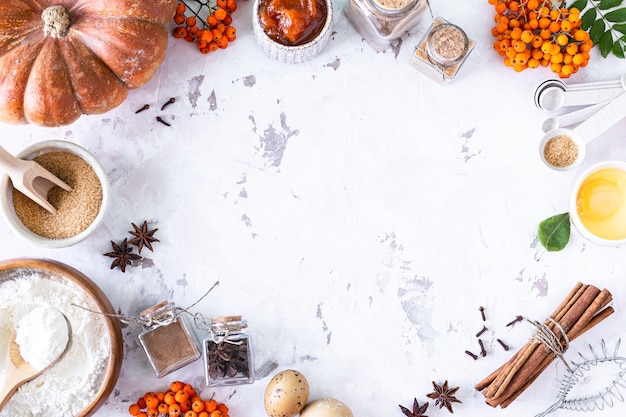 Food ingredients for making autumn pumpkin pie on white stone background. Homemade baking concept. Top view. Copy space