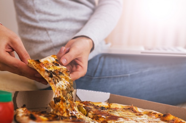 food, italian kitchen and eating concept - close up of hand taking and pizza