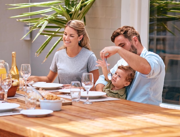 Food mother and father with baby at table at an outdoor patio for holiday celebration with champagne and lunch in summer Happy family mom and dad with child fine dining together at home or house