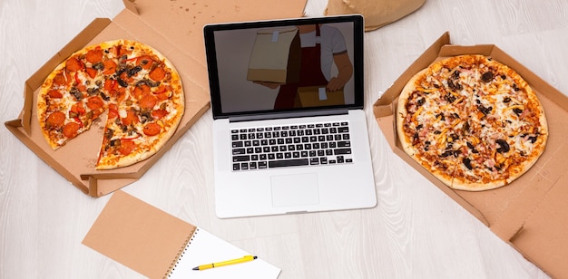 Photo food order concept. close-up top view of a ordering pizza with a laptop. all screen graphics are made up.