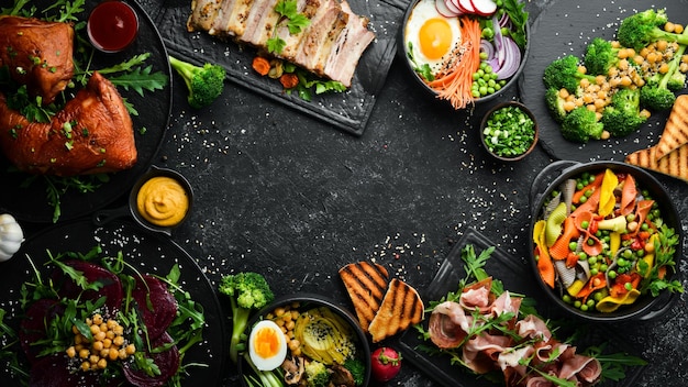 Food pasta pork ribs avocado Buddha bowl and beet salad on a black stone background Top view Free space for text