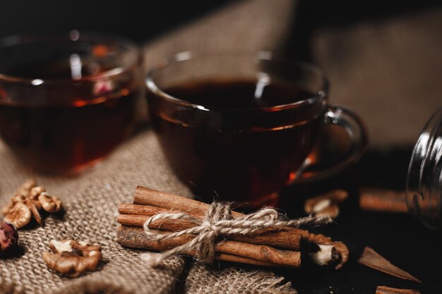 Food photography Cinnamon tied with twine on burlap A glass cup of hot tea on a dark background