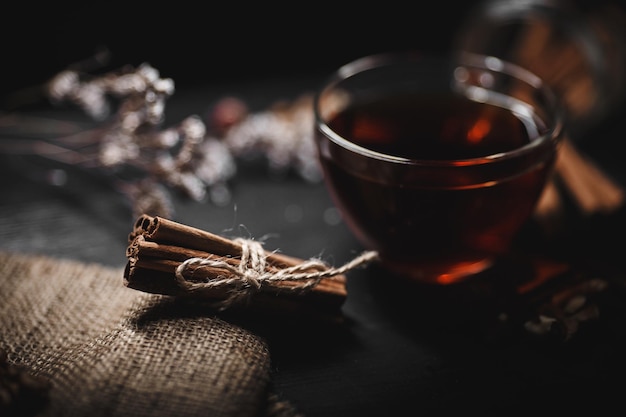 Food photography Cinnamon tied with twine on burlap A glass cup of hot tea on a dark background