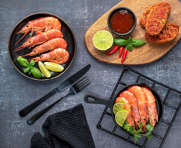 Food photography of shrimps, lime, chile, basil, sauce, on a dark background