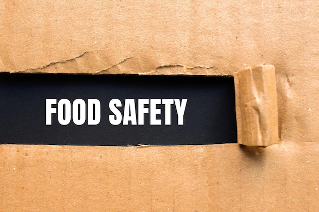 Food safety message written on ripped torn cardboard paper with black background Conceptual food safety symbol Copy space