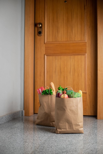 Food shopping bags stand at the door of the house or apartment Vegetables and fruits delivery during quarantine and selfisolation