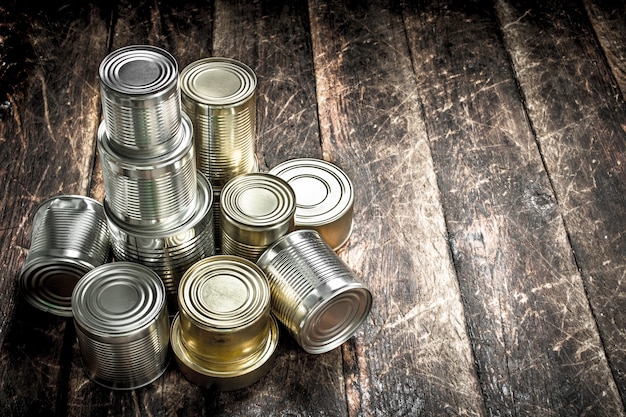 Food in tin cans on wooden table.