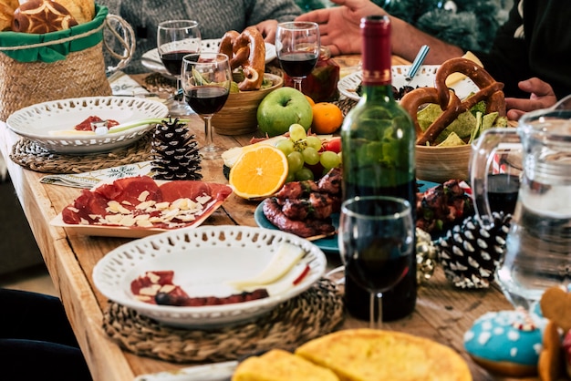 Food with wine bottle and wine glasses on dining table. Sliced meat, fresh fruits with bread placed on table. Fresh cooked food and harvested fruit with wine in bottle and glass.