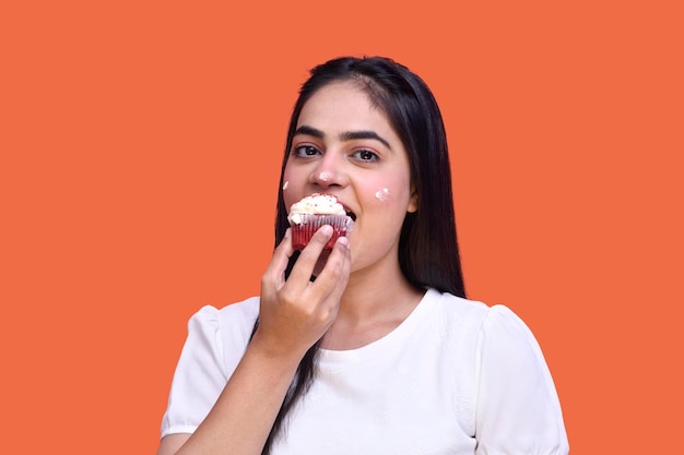 foodie girl wearing tshirt and eating cupcake with hands cream on her face indian pakistani model