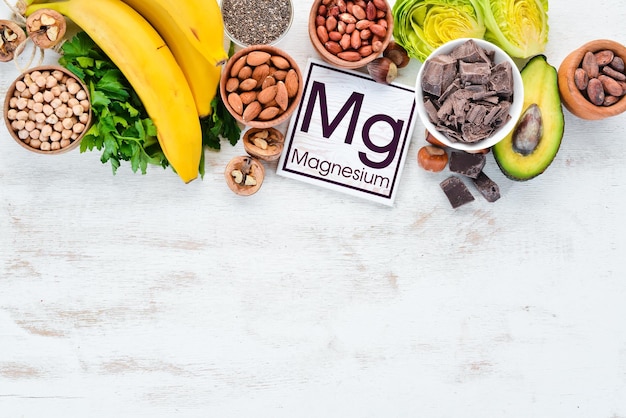 Foods containing natural magnesium Mg Chocolate banana cocoa nuts avocados broccoli almonds Top view On a white wooden background