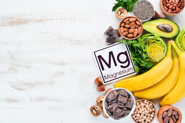 Foods containing natural magnesium Mg Chocolate banana cocoa nuts avocados broccoli almonds Top view On a white wooden background