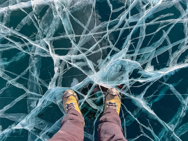 A foot of tourist standing on the cracks surface of frozen lake Baikal in the winter season of Siberia Russia