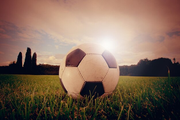 Football ball on the grass at the sunset