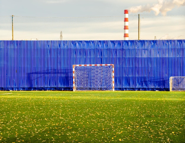 A football field on the background of a factory pipe.