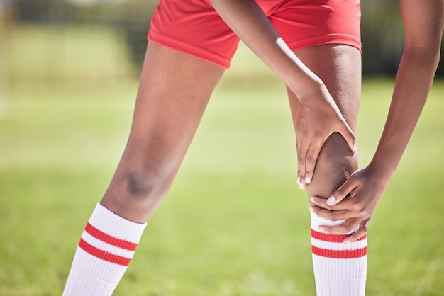 Football knee pain injury of a player hand and leg on a field with closeup for health insurance or anatomy background Below of soccer or sport athlete with broken bone emergency or sports accident