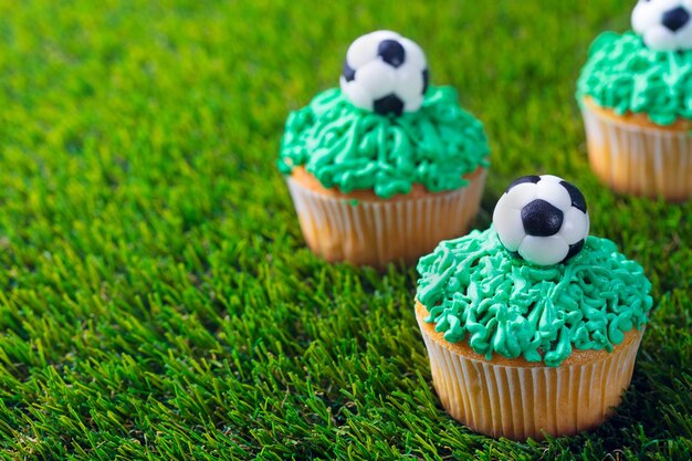 Photo football party birthday decorated cupcake on green grass background copy space