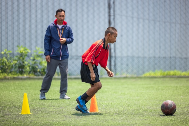 Football soccer training for kids. Coach explaining the game plan. Young boys improving soccer skills local Thailand